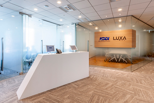エントランスエリア。こちらのオフィスは、エントランスや来客スペース、カフェを同じKDDIグループの株式会社ルクサ(LUXA) と共同利用しているため、エントランスにLUXAのロゴも表示されています。